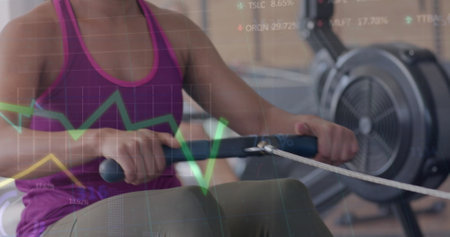 Image of data processing on graph over happy biracial woman training on rowing machine at gym....