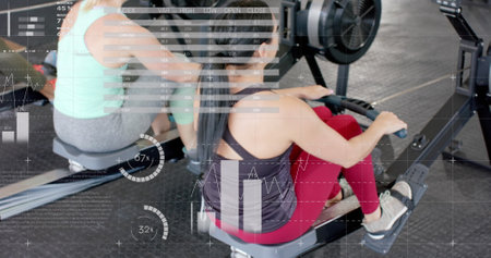 Image of interface processing data over caucasian women training on rowing machines at gym. Fitness, exercise, strength, data, digital interface and technology digitally generated image.の写真素材