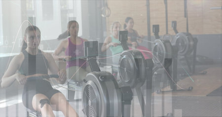 Image of data processing on graph over diverse women cross training on ellipticals at gym. Fitness,...