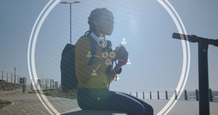Image of technological icons over woman eating sandwich on promenade by the sea. Digital interface...