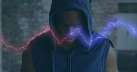 Image of colourful shapes over man wearing a hoodie in an abandoned building. Digital interface...