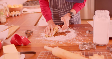 Person kneads dough on a kitchen counter, with copy space. Home baking scene with cookie cutters and rolling pin suggests a cozy domestic activity.の写真素材