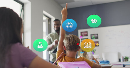 Image of school icons over african american male teacher and pupils raising hands in class. School, education, childhood and learning, digitally generated image.の写真素材