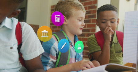 Image of school icons over happy diverse schoolboys looking at schoolbooks. Friendship, school,...