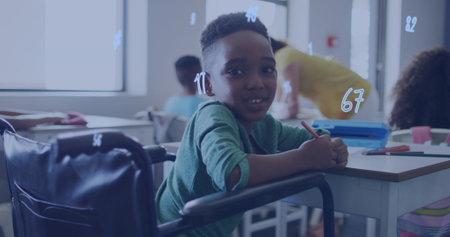 Image of numbers over happy african american schoolboy in wheelchair at desk in class. Disability, inclusivity, school, education, childhood and learning, digitally generated image.の写真素材