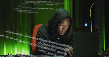 Image of data processing over african american man working on laptop in server room. network, programming, computers and technology concept digitally generated image.の写真素材