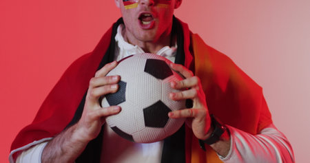 Young Caucasian man poses as a superhero with a soccer ball. His costume suggests a playful take on sports and heroism at a themed event or party.の写真素材