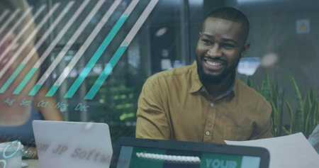 Image of financial data processing over biracial businessman using laptop. Global business, finances, computing and data processing concept digitally generated image.の写真素材