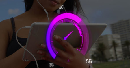 Image of purple speedometer over midsection of biracial woman using tablet. Internet speed, transfer, communication and technology concept digitally generated image.の写真素材