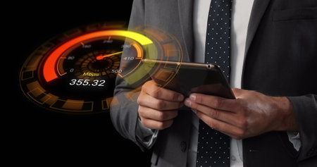 Image of orange speedometer over midsection of caucasian businessman using tablet. Internet speed, transfer, communication and technology concept digitally generated image.の写真素材