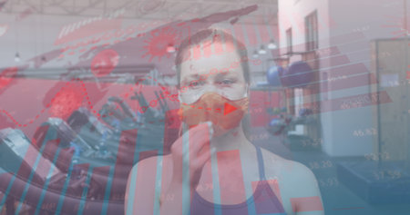Image of floating statistics and graphs over caucasian woman wearing face mask working out. Global covid 19pandemic concept digitally generated image.の写真素材