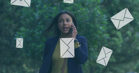 Image of mail message envelope isons over woman talking on smartphone. digital interface, global...