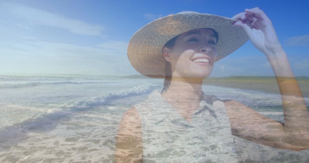 Caucasian woman in a hat walks on the beach.の写真素材