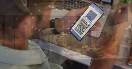 Image of man holding smartphone with covid 19 vaccination passport over people having fun. global covid 19 pandemic and vaccination concept digitally generated image.の写真素材