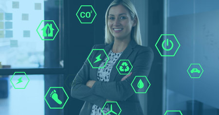 Image of ecology icons over caucasian businesswoman smiling in office. Global business and digital interface concept digitally generated image.の写真素材