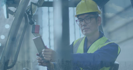 Asian man in safety gear operates machinery at an industrial site. His focus on the task showcases professionalism in a manufacturing environment.の写真素材