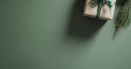 A gift box rests on a green surface, with copy space. The shadow and minimalist presentation suggest a serene and thoughtful gifting moment.の写真素材