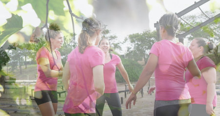 Image of leaves over diverse women at obstacle course high fiving. Global sport, health, fitness and digital interface concept digitally generated image.の写真素材