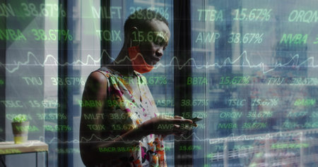 Image of financial data processing over businesswoman with face mask using smartphone in office....