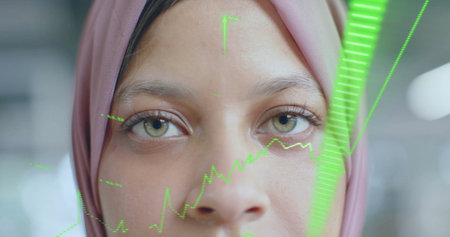Image of financial data processing over biracial businesswoman in hijab in office. Global business,...