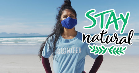 Biracial woman wearing a mask stands on a beach, with copy space. She's volunteering for an...