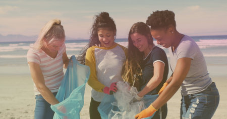 Diverse group of women participate in a beach cleanup. They demonstrate environmental responsibility and teamwork in an outdoor setting.の写真素材