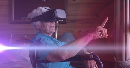 Image of light moving over senior woman in wheelchair using vr headset. retirement, domestic life and hope concept digitally generated image.の写真素材