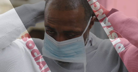 Image of covid 19 social distancing text over african american man putting face mask on. global coronavirus pandemic concept digitally generated image.の写真素材