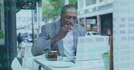 Stock market data processing against african american senior man having a snack while using laptop. global finance and business conceptの写真素材