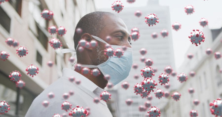 Image of covid 19 cells over african american man wearing face mask. global coronavirus pandemic concept digitally generated image.の写真素材