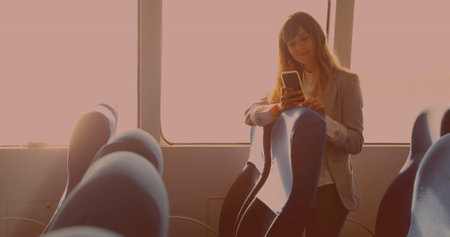 Caucasian businesswoman smiling while using smartphone standing in the bus. Modern technology and people conceptの写真素材