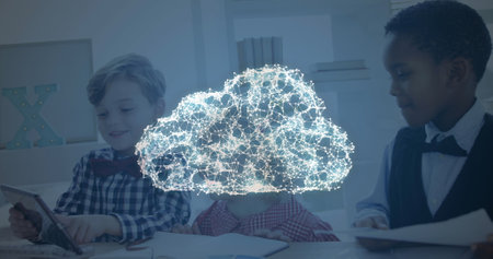 Image of glowing digital cloud icon over schoolchildren sitting at desk in class using digital tablet. Education business social media network interface concept digital composite.の写真素材