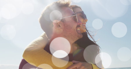 Image of dots over happy caucasian couple having fun on beach. Holidays, vacations and relax concept digitally generated image.の写真素材
