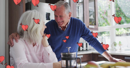 Image of hearts over happy senior caucasian couple drinking coffee. party and celebration concept...