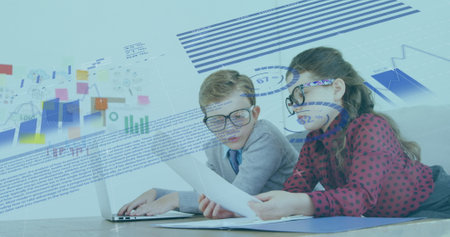 Image of financial data processing over schoolboy and schoolgirl working in an office together, using laptop computer, reading. Education business economy interface concept digital composite.の写真素材