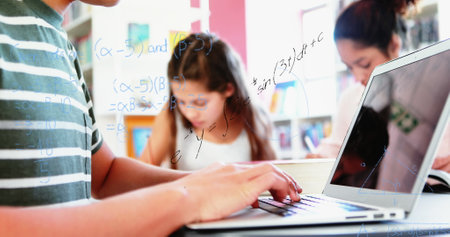 Image of mathematical equations floating over schoolchild using laptop computer with classmates in the background. Education back to school concept digitally generated image.の写真素材
