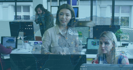Image of data processing and world map over two diverse female colleagues discussing at office. Computer interface and business technology conceptの写真素材