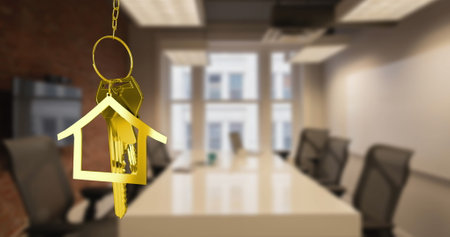 Image of hanging golden house keys against interior of a office conference room. Interior designing and real estate conceptの写真素材