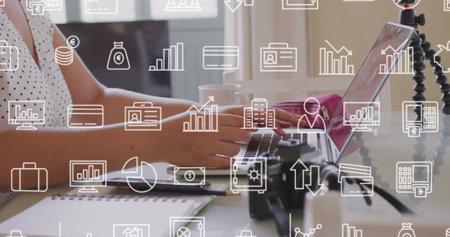 Image of multiple icons over midsection of caucasian woman using laptop. Digital composite, multiple exposure, report, business, banking, finance, education and technology concept.の写真素材