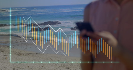 Image of graphs over caucasian female typing on cellphone while standing against sea. Digital...