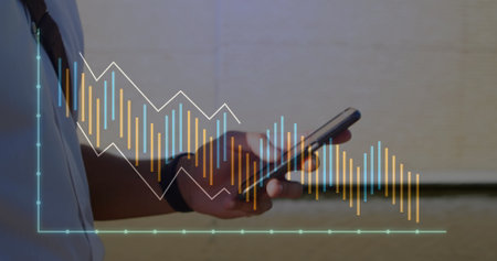 Image of graphs over midsection of caucasian man walking while texting on smartphone. Digital composite, multiple exposure, illuminated, report, business and technology concept.の写真素材