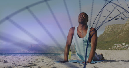African American male, fitness enthusiast, sitting on beach, meditating. Wearing sleeveless top, revealing strong, fit physique, enjoying serene blue backgroundの写真素材