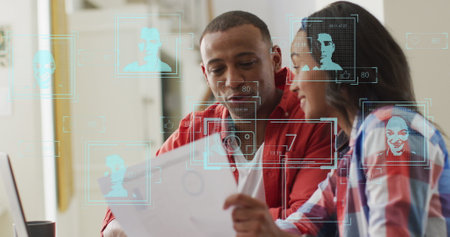 Image of profile icons over african american man and woman discussing over document at office. Global networking and business technology conceptの写真素材