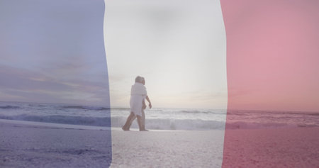 Image of flag of france over senior biracial couple walking at beach. Bastille day, fete nationale francaise, patriotism and celebration concept digitally generated image.の写真素材