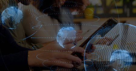 Image of globes and spiral pattern, cropped hands of caucasian woman using digital tablet. Digital composite, multiple exposure, business, globalization, office and technology concept.の写真素材
