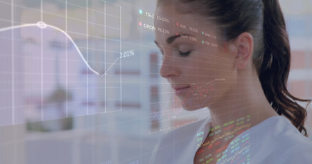 Caucasian woman with light skin and brown hair in ponytail studying financial graphs. Young woman...