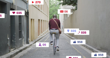 Image of social media text and icons over caucasian man riding bike in city. Global social media, digital interface, computing and data processing concept digitally generated image.の写真素材