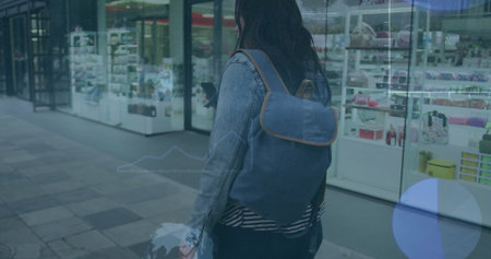 Image of graphs and gloves over biracial woman scrolling on cellphone while walking on street....