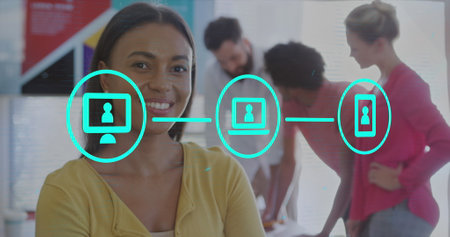 Image of flowchart of icons over smiling biracial woman standing arms crossed in office. Digital composite, multiple exposure, business, abstract, communication and technology concept.の写真素材