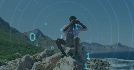 Image of binary codes, circles over african american man looking through binoculars at outdoor. Digital composite, multiple exposure, shape, computer language and technology concept.の写真素材